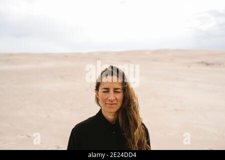 Femme avec les yeux fermés, dunes de sable sur fond Banque D'Images