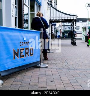Londres Royaume-Uni, une femme debout seule à l'extérieur D'UN café Nero Coffee Shop sur et vide High Street pendant Covid-19 pandémie Lockdown Banque D'Images