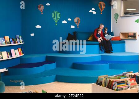 Grand-père lisant le livre aux petits-fils dans la bibliothèque Banque D'Images