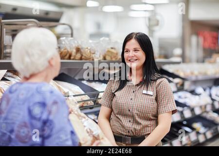 Femme au supermarché qui parle à l'employé du magasin Banque D'Images