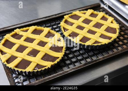 Deux gâteaux ou tartes au chocolat fraîchement cuits sur des plaques de cuisson se tenir sur une grille métallique pour refroidir à la fermeture un grand angle sur un comptoir de cuisine Banque D'Images