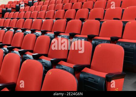 Rangées de chaises rouges vides à plusieurs niveaux dans un auditorium vue rapprochée avec un angle oblique dans un divertissement ou concept des arts de la scène Banque D'Images