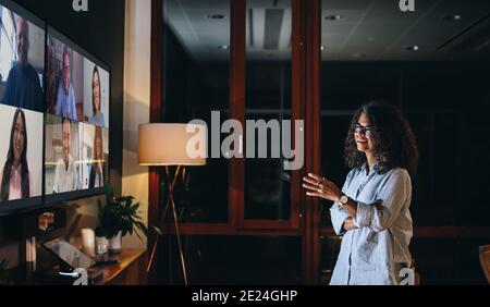 femme d'affaires parlant à des coéquipiers lors d'un appel vidéo de fin de nuit. Entrepreneur parlant avec des collègues sur la télévision lcd. Banque D'Images