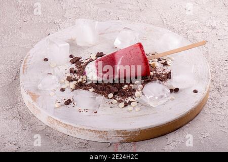 Glace à la fraise popsicle sucettes aux crèmes fouettées au chocolat et glaçons sur fond de bois blanc. Vue de dessus Banque D'Images