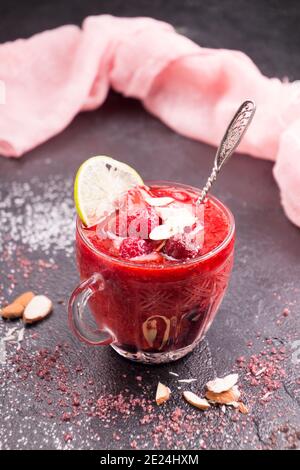 Mélanger le smoothie à la fraise avec des fraises entières, de la glace et du citron dans des verres sur fond noir. Concept de régime alimentaire sain. Banque D'Images