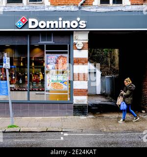 Londres, Royaume-Uni, janvier 03 2021, le logo du restaurant Dominos Pizza Takeaway et le front de vente avec UNE personne marchant sur le trottoir Banque D'Images