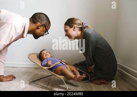 Parents regardant bébé couché dans le bouteur Banque D'Images