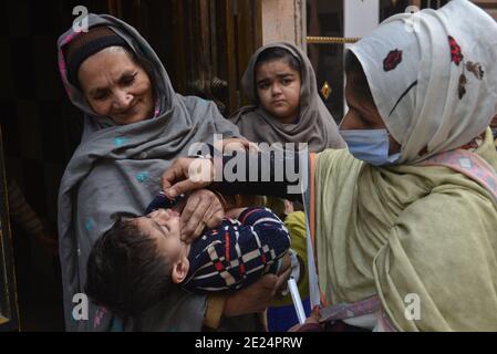 Un travailleur de la santé pakistanais administre un vaccin contre la polio à un enfant Au cours d'une campagne de vaccination de porte à porte contre la polio à Lahore Banque D'Images