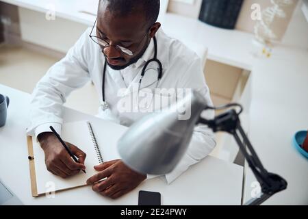 Medic concentré à l'aide d'un crayon pour enregistrer les informations Banque D'Images