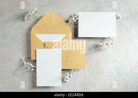 Ensemble de papeterie de mariage vue du dessus. Des enveloppes en papier Kraft et une carte en papier vierge sont décorées de fleurs sur une table en pierre. Style vintage. Pose à plat. Banque D'Images