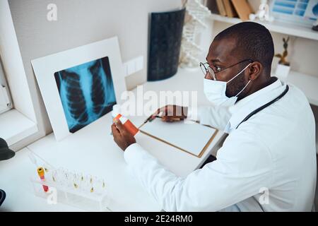 Employé de l'hôpital donnant un regard sérieux tout en tenant le flacon de pilule Banque D'Images