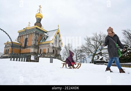 Darmstadt, Allemagne. 12 janvier 2021. Kathleen Lebsa de Darmstadt tire sa petite fille Antonia sur un traîneau au-dessus de la neige de Mathildenhöhe avec la chapelle russe. Credit: Arne Dedert/dpa/Alay Live News Banque D'Images