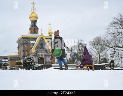 Darmstadt, Allemagne. 12 janvier 2021. Kathleen Lebsa de Darmstadt tire sa petite fille Antonia sur un traîneau au-dessus de la neige de Mathildenhöhe avec la chapelle russe. Credit: Arne Dedert/dpa/Alay Live News Banque D'Images