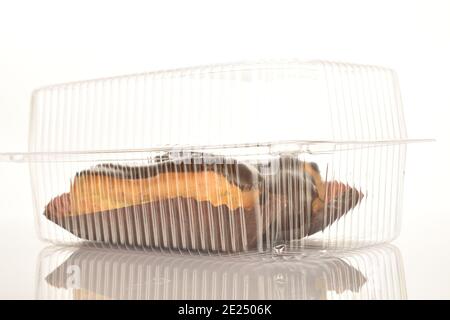 Deux eclaloires au chocolat dans un récipient en plastique, en gros plan, isolées sur du blanc. Banque D'Images