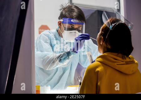 Manille, Philippines. 12 janvier 2021. Un professionnel de la santé qui porte un équipement de protection individuelle effectue un test COVID-19 sur une femme à la Croix-Rouge philippine à Manille, aux Philippines, le 12 janvier 2021. Le ministère de la Santé des Philippines a signalé mardi 1,524 nouveaux cas confirmés de COVID-19, portant le nombre total de cas dans le pays à 491,258. Crédit: Rouelle Umali/Xinhua/Alamy Live News Banque D'Images