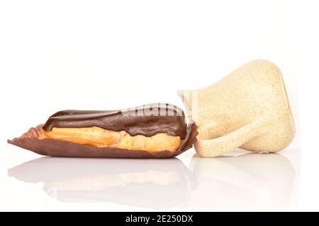 Un chocolat eclair avec un pot à lait en céramique, gros plan, isolé sur du blanc. Banque D'Images