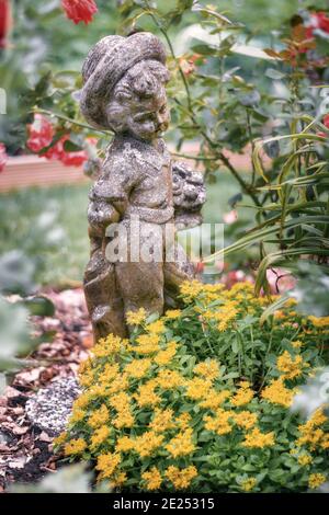 Sculpture d'un petit garçon parmi les fleurs dans un jardin frontière quelque part aux pays-Bas Banque D'Images