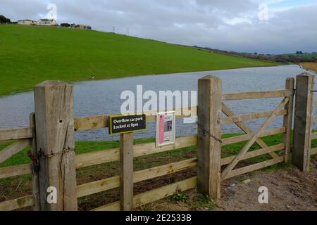 Vue sur le parc de stationnement inondé avec un panneau descriptif sur la clôture. South Milton Ley Reserve, Thurlestone, South Devon, Royaume-Uni Banque D'Images