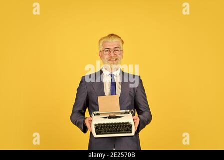 Les vieux habitudes de l'auteur de bâton. Les hommes d'affaires utilisent la technologie rétro. Homme mûr teint les cheveux de barbe fond jaune. Magasin de marchandises d'occasion. Objets anciens du vendeur. Connaisseur des valeurs vintage. Machine à écrire vintage. Banque D'Images
