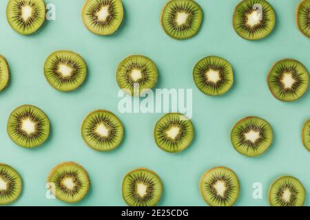 Les motifs des tranches de kiwi sur fond vert comme fond continu. Fond de fruit conceptuel texturé Banque D'Images