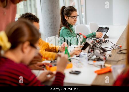 Femme afro-américaine smily enseignant en sciences avec un groupe d'enfants programmation de jouets électriques et de robots dans les salles de classe de robotique Banque D'Images