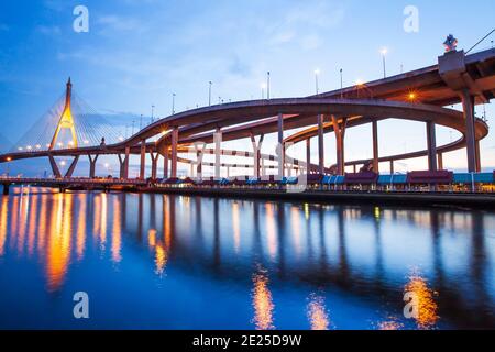 Magnifique vue à angle bas de l'échangeur de l'autoroute et des ponts suspendus au crépuscule, les lumières se reflètent sur la rivière Chao Phraya. Pont Bhumibol, Thaïlande. Banque D'Images