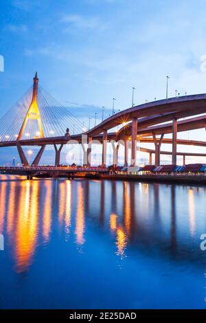 Magnifique vue à angle bas de l'échangeur de l'autoroute et des ponts suspendus au crépuscule, les lumières se reflètent sur la rivière Chao Phraya. Pont Bhumibol, Thaïlande. Banque D'Images