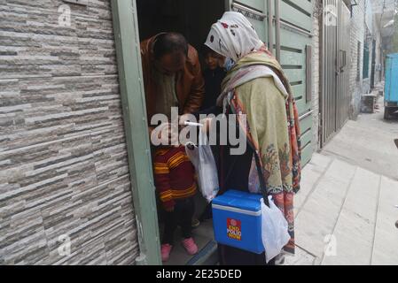 Lahore, Pakistan. 12 janvier 2021. Un travailleur de la santé pakistanais administre un vaccin contre la polio à un enfant lors d'une campagne de vaccination de porte à porte contre la polio à Lahore. Malgré une augmentation constante des cas de coronavirus, le Pakistan a lancé lundi une campagne de vaccination de cinq jours contre la polio dans des conditions de sécurité étroite, dans l'espoir d'éradiquer cette maladie invalidante pour les enfants cette année. (Photo de Rana Sajid Hussain/Pacific Press) Credit: Pacific Press Media production Corp./Alay Live News Banque D'Images