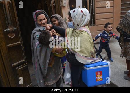 Lahore, Pakistan. 12 janvier 2021. Un travailleur de la santé pakistanais administre un vaccin contre la polio à un enfant lors d'une campagne de vaccination de porte à porte contre la polio à Lahore. Malgré une augmentation constante des cas de coronavirus, le Pakistan a lancé lundi une campagne de vaccination de cinq jours contre la polio dans des conditions de sécurité étroite, dans l'espoir d'éradiquer cette maladie invalidante pour les enfants cette année. (Photo de Rana Sajid Hussain/Pacific Press) Credit: Pacific Press Media production Corp./Alay Live News Banque D'Images