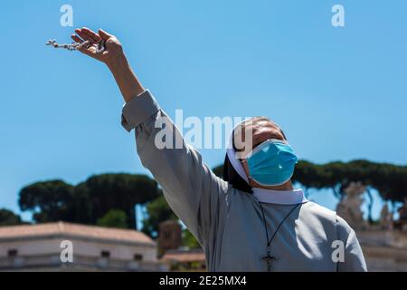 Une religieuse portant un masque protecteur priant le Saint rosaire de la place Saint-Pierre au Vatican le 31 mai 2020, pendant la prière du Pape François Regina Coeli Banque D'Images