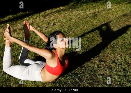 Jeune femme faisant du yoga dans un jardin à Eure, France Banque D'Images