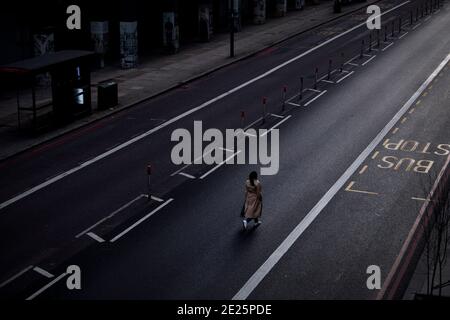 Une femme seule marche au milieu d'une route principale vide à Westminster, dans le centre de Londres, pendant le troisième confinement national de l'Angleterre pour freiner la propagation du coronavirus continue. Banque D'Images