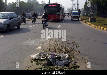 Les navetteurs passent à proximité d'un trou d'égout principal ouvert qui peut causer tout accident, en particulier la nuit, montrant la négligence des départements concernés, sur la route Wahdat à Lahore le mardi 12 janvier 2021. Banque D'Images