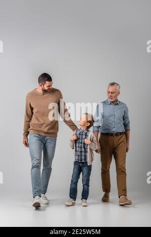 joyeux garçon regardant le père en marchant près de grand-père gris Banque D'Images