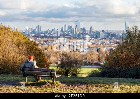 Un homme assis sur un banc qui regarde la vue de l'autre côté de la ville depuis la colline du Parlement pendant le confinement en cas de pandémie du coronavirus, Londres, Royaume-Uni Banque D'Images