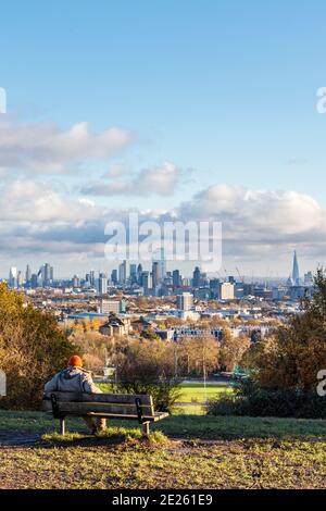 Un homme assis sur un banc qui regarde la vue de l'autre côté de la ville depuis la colline du Parlement pendant le confinement en cas de pandémie du coronavirus, Londres, Royaume-Uni Banque D'Images