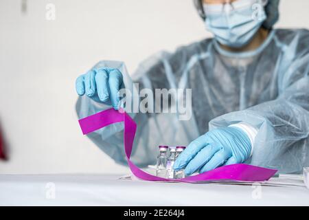 Scientifique portant des vêtements très protecteurs tenant un tube montrant positif Résultat du test Covid Banque D'Images