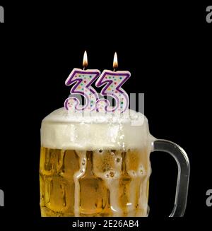numéro 33 bougies dans la tasse à bière pour la fête d'anniversaire isolé sur le noir Banque D'Images