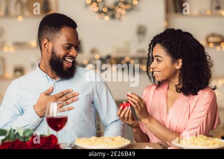 Femme noire souriante faisant la proposition avec anneau à son homme Banque D'Images