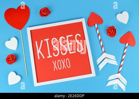 Jolie composition de la Saint-Valentin avec cadre photo avec texte « KISSES XOXO », flèches d'amour de cupid et coeurs sur fond bleu Banque D'Images