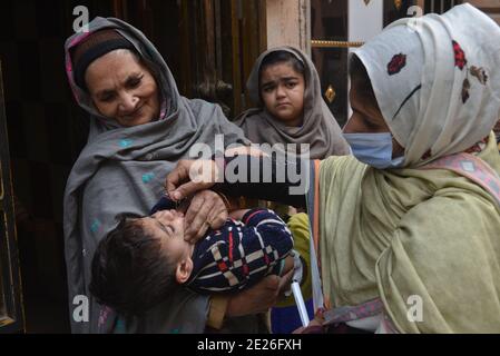 Lahore, Pakistan. 12 janvier 2021. Un travailleur de la santé pakistanais administre un vaccin contre la polio à un enfant lors d'une campagne de vaccination de porte à porte contre la polio à Lahore. Malgré une augmentation constante des cas de coronavirus, le Pakistan a lancé lundi une campagne de vaccination de cinq jours contre la polio dans des conditions de sécurité étroite, dans l'espoir d'éradiquer cette maladie invalidante pour les enfants cette année. (Photo de Rana Sajid Hussain/Pacific Press/Sipa USA) crédit: SIPA USA/Alay Live News Banque D'Images