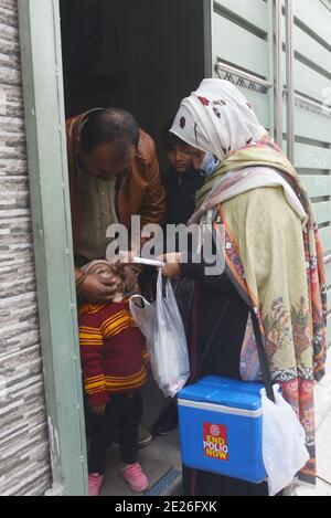 Lahore, Pakistan. 12 janvier 2021. Un travailleur de la santé pakistanais administre un vaccin contre la polio à un enfant lors d'une campagne de vaccination de porte à porte contre la polio à Lahore. Malgré une augmentation constante des cas de coronavirus, le Pakistan a lancé lundi une campagne de vaccination de cinq jours contre la polio dans des conditions de sécurité étroite, dans l'espoir d'éradiquer cette maladie invalidante pour les enfants cette année. (Photo de Rana Sajid Hussain/Pacific Press/Sipa USA) crédit: SIPA USA/Alay Live News Banque D'Images