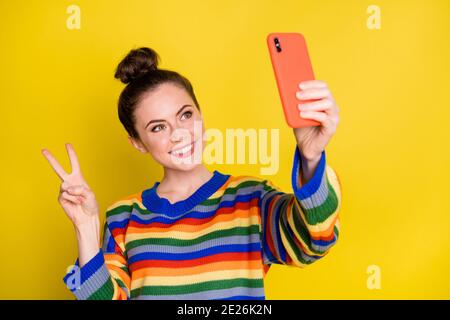 Photo d'une jolie petite fille aux cheveux de pain brun faire un spectacle de selfie v-sign wear chandail de couleur arc-en-ciel isolé sur fond jaune Banque D'Images