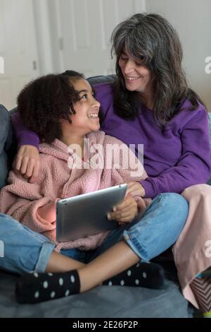 La mère caucasienne et la fille bi-raciale avant l'adolescence se sourient l'une à l'autre Banque D'Images