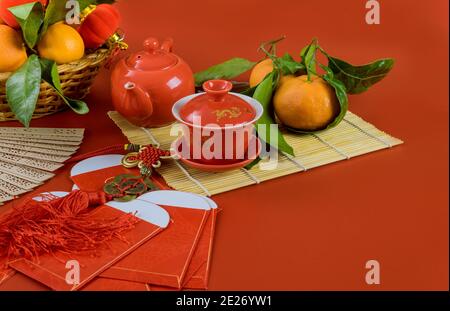 Top vue accessoires festival chinois du nouvel an décorations de mandarines Paquet de feuilles rouge Ang Pau pour argent avec thé de cérémonie saison sur fond rouge Banque D'Images