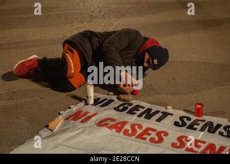 Barcelone, Catalogne, Espagne. 12 janvier 2021. L'homme couché est vu allumer la bougie en hommage aux sans-abri qui sont morts du froid.The Housing Union, de Barceloneta, un quartier de Barcelone, Ont appelé à un rassemblement pour deux résidents du quartier qui vivaient dans la rue et ont été les victimes fatales de la vague de froid qui hante l'Espagne. Les manifestants ont rendu hommage aux victimes et exigé un foyer digne pour tous les habitants de la rue. Credit: Thiago Prudencio/DAX/ZUMA Wire/Alay Live News Banque D'Images