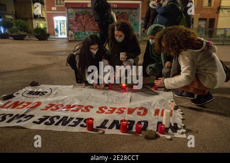 Barcelone, Catalogne, Espagne. 12 janvier 2021. Les femmes ont vu des bougies d'éclairage pour les sans-abri morts.le syndicat du logement, de Barceloneta, un quartier de Barcelone, ont appelé un rassemblement pour deux résidents du quartier qui ont vécu dans la rue et ont été les victimes fatales de la vague froide qui hante l'Espagne. Les manifestants ont rendu hommage aux victimes et exigé un foyer digne pour tous les habitants de la rue. Credit: Thiago Prudencio/DAX/ZUMA Wire/Alay Live News Banque D'Images