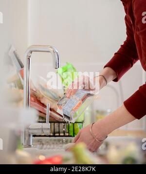 Un propriétaire lavant la livraison de l'épicerie dans de l'eau chaude savonneuse. Une partie de la vie quotidienne dans le cadre du troisième confinement des covidés dans un ménage britannique. Banque D'Images