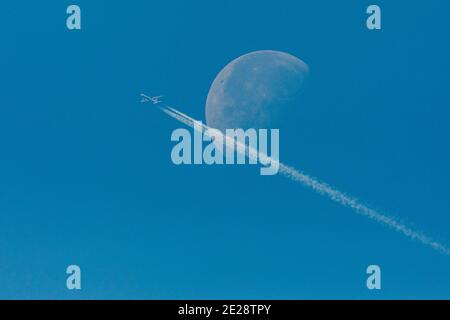 Lune en déclin, en premier plan un avion de ligne commercial avec des contrailles, Allemagne, Bavière Banque D'Images