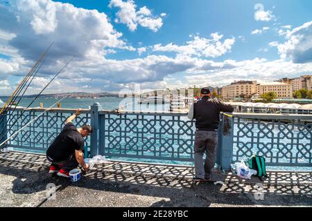 Les pêcheurs turcs locaux pendent leurs pôles de pêche au large du pont de Galata, avec le quartier de Sultanahmet au loin. Banque D'Images